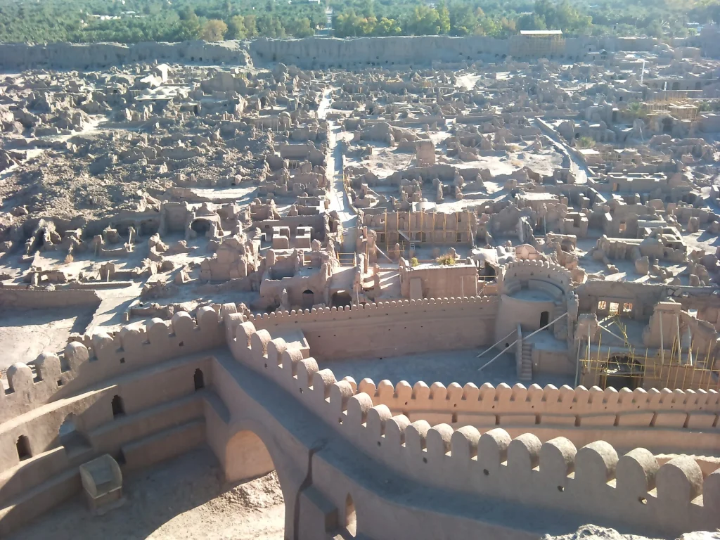نمای ارگ بم در جریان مرمت، خانه‌های خشتی و نخلستان‌های پشت حصار در آذر ۱۳۹۰